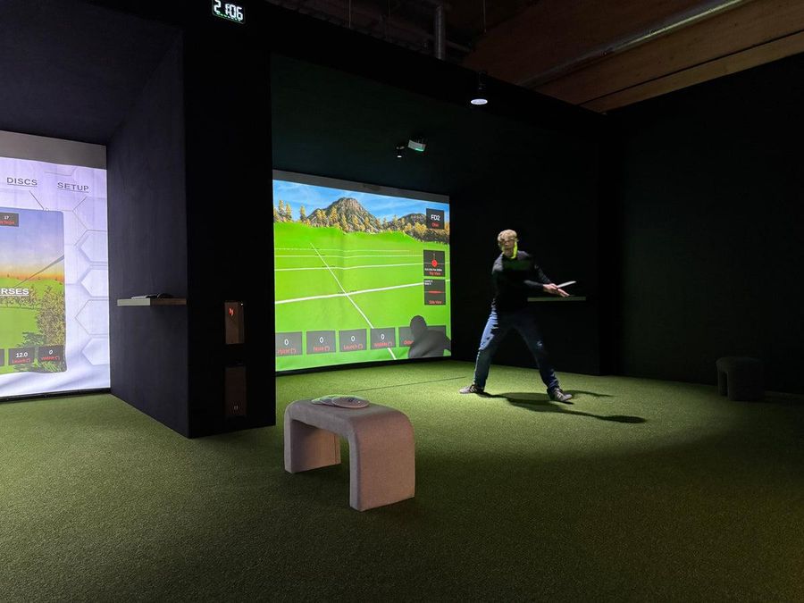 Person spelar på en HYZR discgolfsimulator inomhus